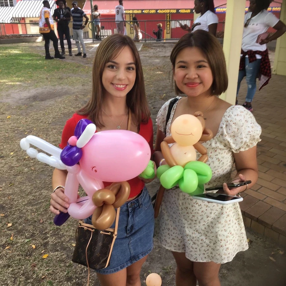 two girls with unicorn and money balloon animals