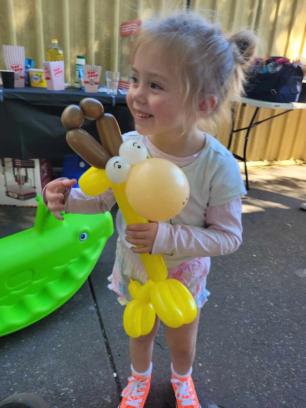 smiling girl with a giraffe balloon animal